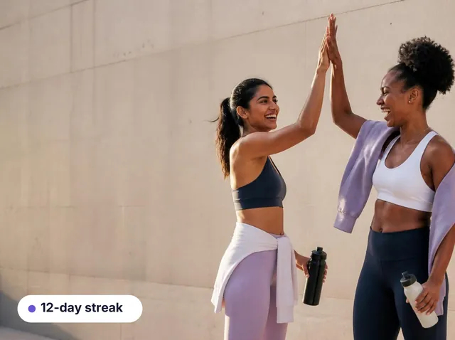 Two women high-fiving after a workout, with a 12-day streak card